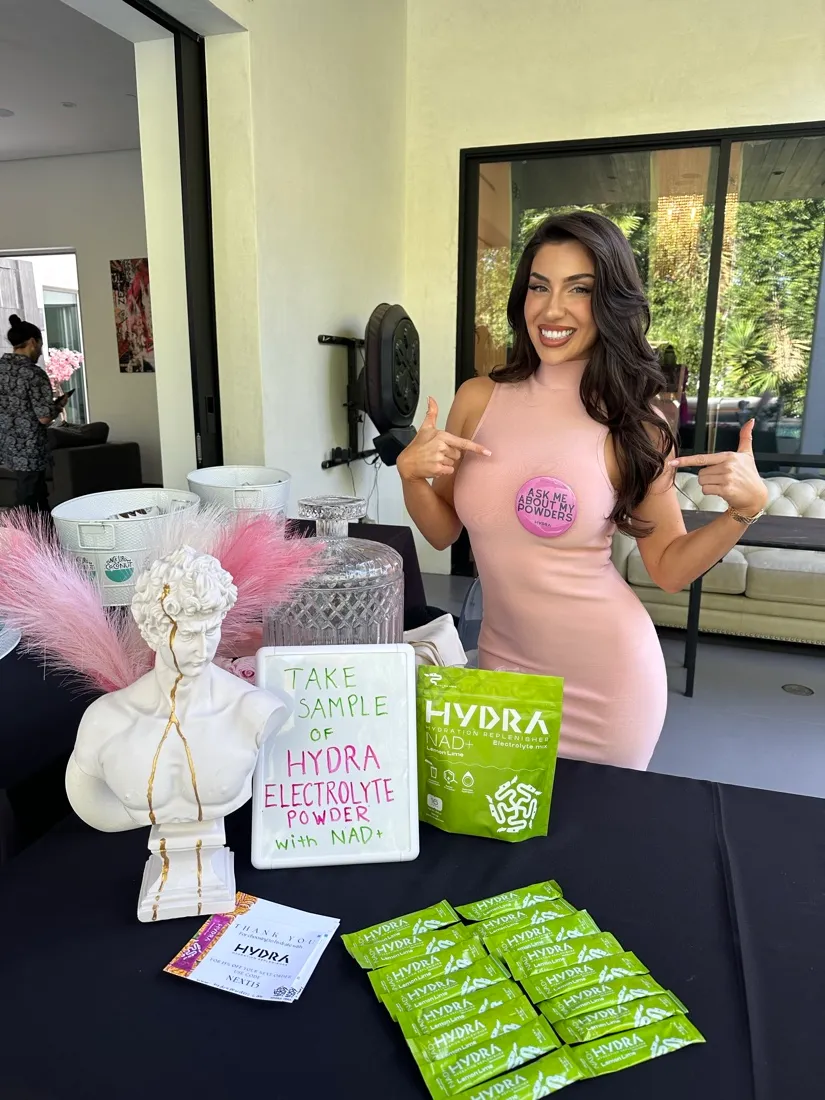 Lauren at a Hydra Powders sampling table wearing an "ask me about my powders" pin.