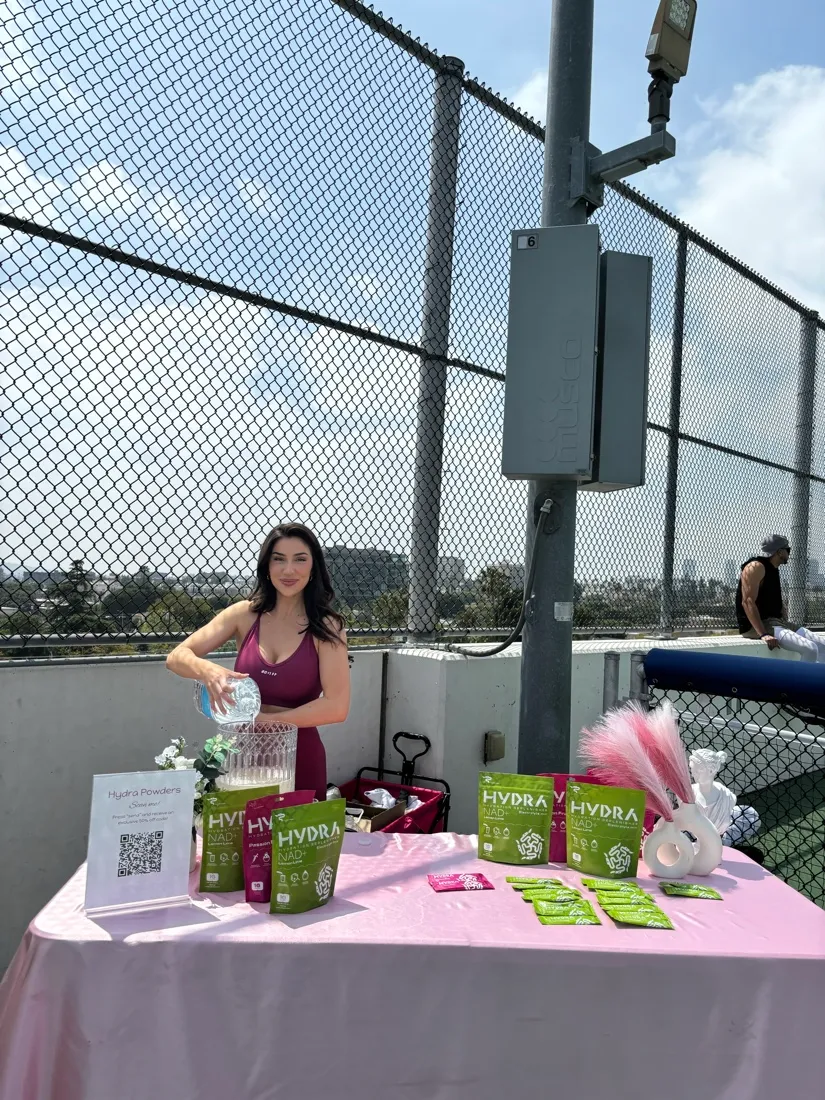 Lauren pouring samples at a Hydra Powders table on a rooftop court.