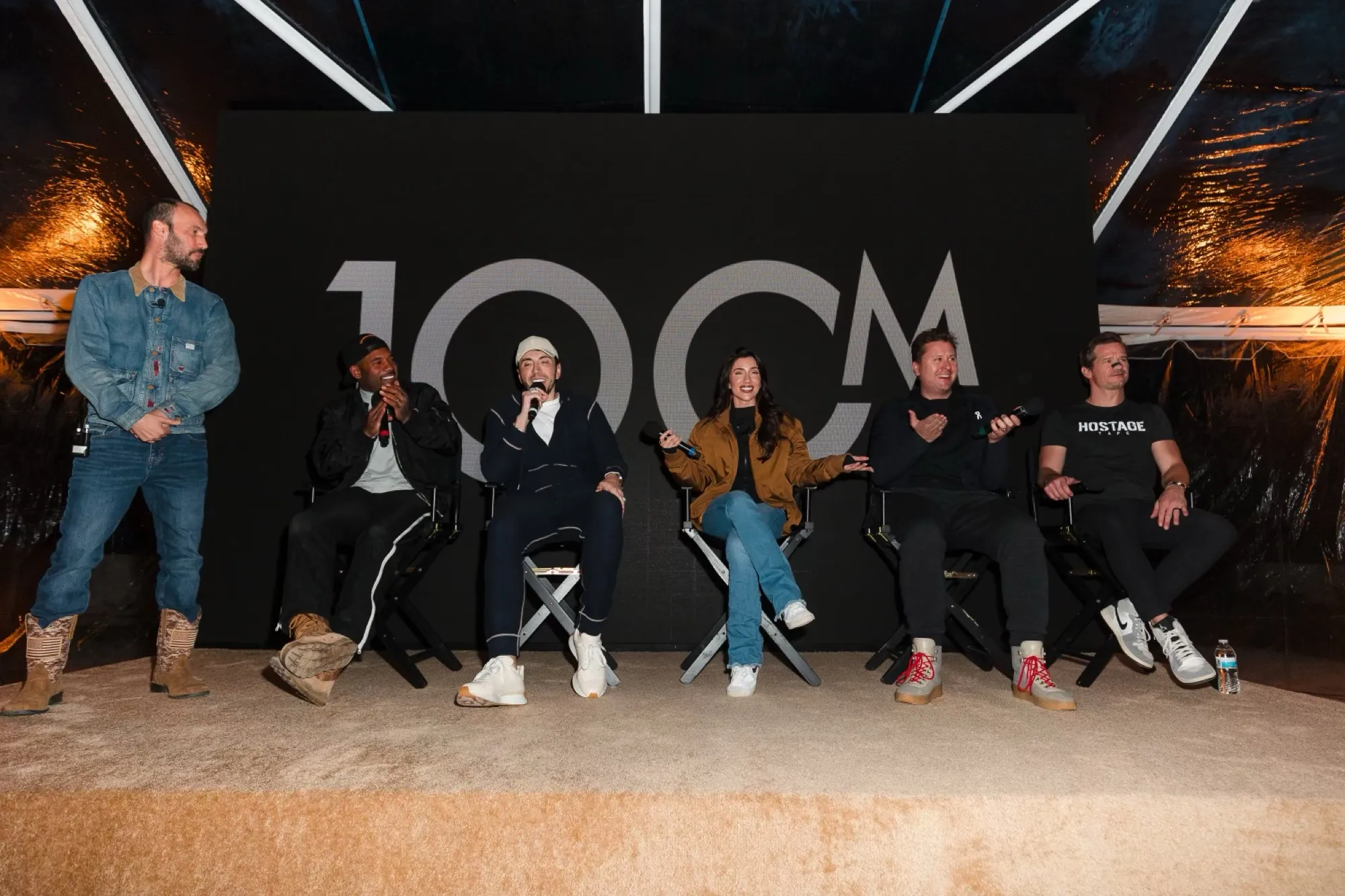 Lauren on a six-person panel on stage in front of a 100M backdrop.